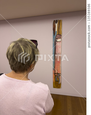 Person visiting art museum in Porto Serralves. Woman looking at painting in gallery hall, 135169386