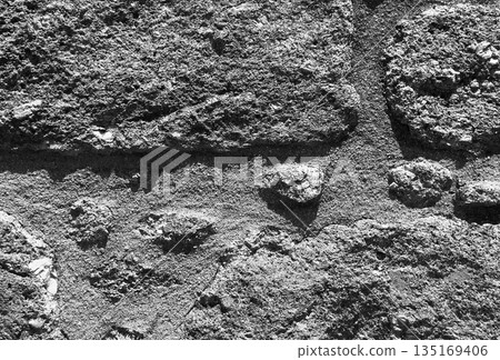 Stone wall with grey textured surface. Old weathered rock pattern with rough masonry blocks, cracked 135169406