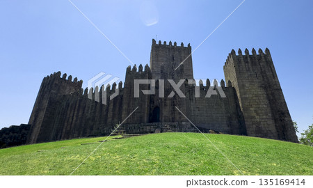 Tower of mediaeval castle in Guimaraes Portugal. Historic stone fortress with battlement walls on 135169414