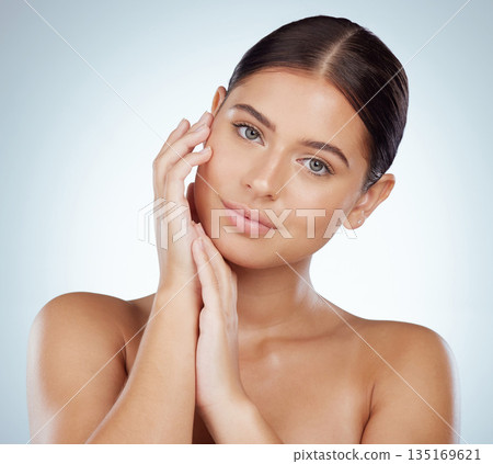 Face, skincare and hands of woman in studio isolated on white background. Portrait, natural beauty and serious female model in makeup, cosmetics or facial treatment for health, aesthetic or wellness 135169621