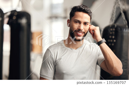 Fitness, gym and a man with earphones for music for wellness, health and training with a smile. Face portrait of a person listening to audio, radio or podcast for exercise or workout at wellness club Fitness, gym and a man with earphones for music for wellness, health and training with a smile. Face portrait of a person listening to audio, radio or podcast for exercise or workout at wellness club 135169707