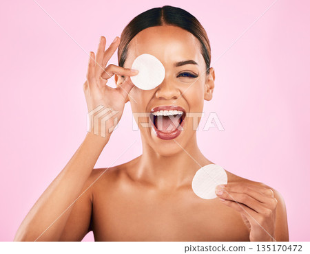 Happy woman, face and cotton pad in skincare, makeup removal or cosmetics against a pink studio background. Portrait of excited female person with cosmetic swab in beauty cleaning or facial treatment Happy woman, face and cotton pad in skincare, makeup removal or cosmetics against a pink studio background. Portrait of excited female person with cosmetic swab in beauty cleaning or facial treatment 135170472