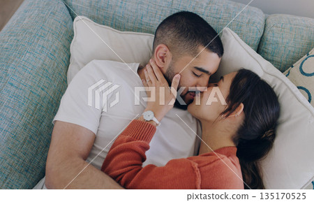 Top view of couple, love and kiss on sofa in living room for romance, intimacy and relax together at home. Young man, woman and kissing partner on couch for happy relationship, quality time and care Top view of couple, love and kiss on sofa in living room for romance, intimacy and relax together at home. Young man, woman and kissing partner on couch for happy relationship, quality time and care 135170525
