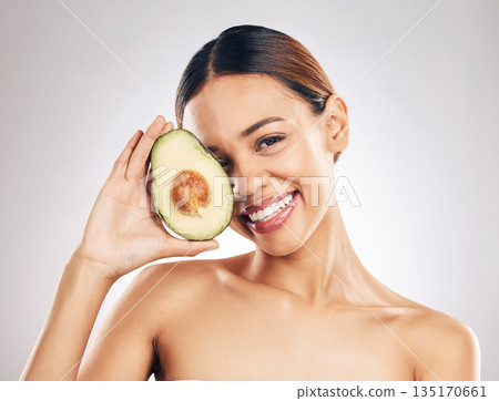 Woman, skincare and avocado in studio portrait for health, wellness or facial glow by white background. Girl, model and healthy skin with fruit, makeup or cosmetics for self care, aesthetic and smile 135170661