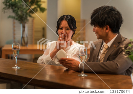 A man makes a surprise proposal at a bar counter to a surprised woman 135170674