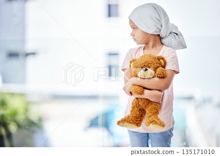 Healthcare, teddy bear and child cancer patient holding her toy for support or comfort. Medical, recovery and girl kid with leukemia standing after treatment or chemotherapy in a medicare hospital. Healthcare, teddy bear and child cancer patient holding her toy for support or comfort. Medical, recovery and girl kid with leukemia standing after treatment or chemotherapy in a medicare hospital. 135171010