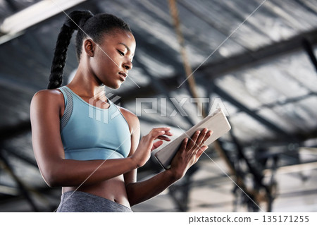 Black woman, typing or personal trainer with a tablet for fitness training, workout or sports exercise. Progress results, digital technology app or gym instructor planning a online coaching schedule 135171255