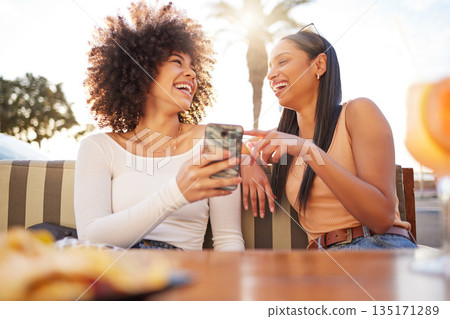 Laughing, happy and women with a phone at a cafe for a meme or social media notification. Smile, talking and friends with a mobile for a funny app, comic conversation or comedy together at restaurant Laughing, happy and women with a phone at a cafe for a meme or social media notification. Smile, talking and friends with a mobile for a funny app, comic conversation or comedy together at restaurant 135171289