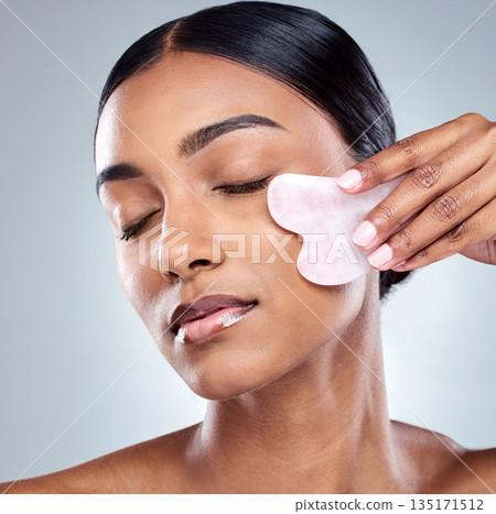 Massage, skincare and gua sha with face of woman in studio for beauty, wellness and cosmetics. Spa, self care and glow with model on grey background for facial, cosmetology and rose quartz crystal Massage, skincare and gua sha with face of woman in studio for beauty, wellness and cosmetics. Spa, self care and glow with model on grey background for facial, cosmetology and rose quartz crystal 135171512