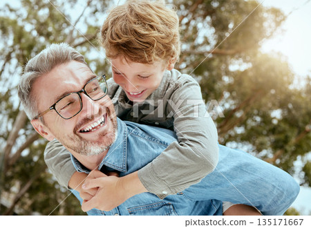 Piggyback, fun and father with child in a park happy, playing and having fun in nature. Hug, love and parent carrying son in a garden, laughing and enjoying games, smile and together on the weekend 135171667