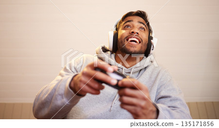 Man play video games, headphones and controller for esports, online streaming and happy at home. Male gamer, smile with entertainment and excited about gaming competition, tech and cyber streamer Man play video games, headphones and controller for esports, online streaming and happy at home. Male gamer, smile with entertainment and excited about gaming competition, tech and cyber streamer 135171856