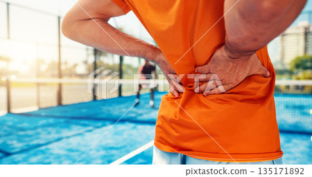 Hands, person and back pain on tennis court for fitness, match accident and muscle sprain. Player, discomfort and joint strain of exercise mistake, inflammation and sports injury from tournament game Hands, person and back pain on tennis court for fitness, match accident and muscle sprain. Player, discomfort and joint strain of exercise mistake, inflammation and sports injury from tournament game 135171892