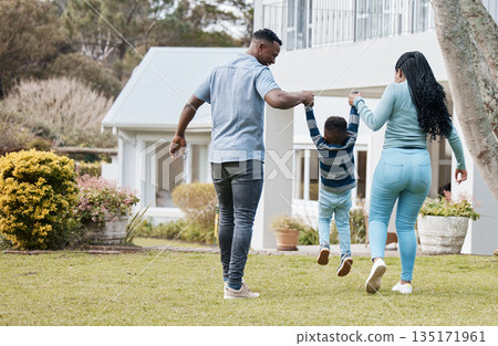 Mother and father lifting child by their new home in the outdoor garden while playing together. Backyard, bonding and back of African parents holding their boy kid in the backyard of their house. 135171961