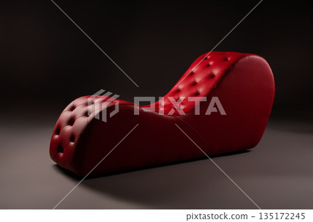 Luxurious red tufted ergonomic chaise lounge chair on a dark gray studio background. 135172245