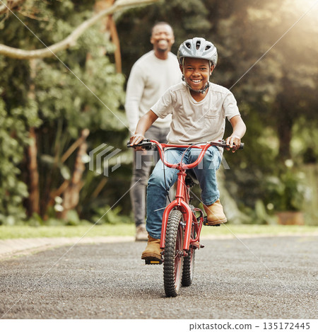 Boy with smile on bicycle, father and learn cycling with help, helmet for safety and family in park. Support, motivation and trust, black man and young kid outdoor, teaching and learning bike riding 135172445