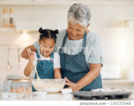 Bake, grandmother and girl with ingredients, learning and development with utensils, food or love. Family, granny or female grandchild in a kitchen, dough or teaching skills with happiness or bonding Bake, grandmother and girl with ingredients, learning and development with utensils, food or love. Family, granny or female grandchild in a kitchen, dough or teaching skills with happiness or bonding 135172548