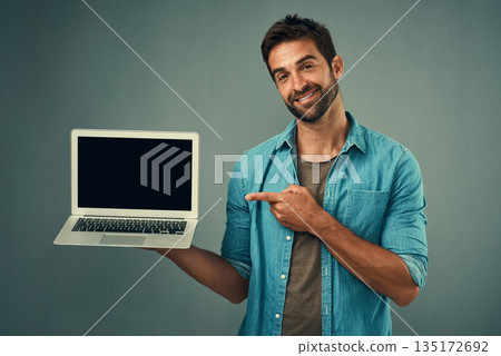 Happy man, laptop and pointing to mockup screen for advertising or marketing against a grey studio background. Portrait of male person showing computer display or mock up space for advertisement Happy man, laptop and pointing to mockup screen for advertising or marketing against a grey studio background. Portrait of male person showing computer display or mock up space for advertisement 135172692