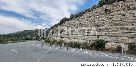 Mountain road curve with rocky cliff 135173016