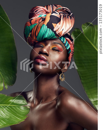 Beauty, leaf and makeup by black woman in studio for self love or natural cosmetics on grey background. Culture, monstera and face of African lady model with plant for dermatology or jungle aesthetic 135173019
