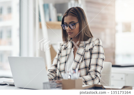 Laptop, copywriter and business woman typing in office workplace. Writer, computer and female Indian person reading, working and writing email, report or proposal, research online or planning project 135173164