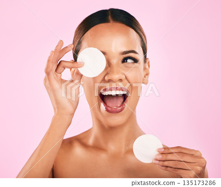 Happy woman, face and cotton pad in beauty, makeup removal or skincare cosmetics against a pink studio background. Excited female person or model with cosmetic swab for cleaning or facial treatment 135173286