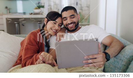 Tablet, happy couple and relax on couch in home for social media, online entertainment and love. Young man, woman and digital technology for web subscription, streaming movie and network connection 135173306