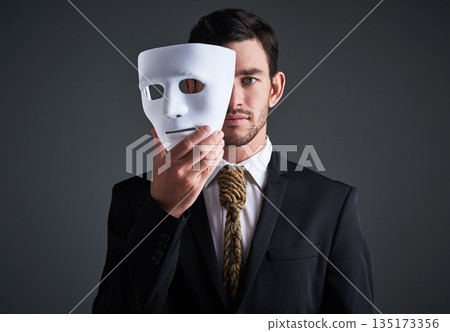 Two faces, holding mask and businessman portrait in a studio with serious face with secret and fraud. Worker or corporate criminal with rope tie showing identity theft or liar in business suit mockup Two faces, holding mask and businessman portrait in a studio with serious face with secret and fraud. Worker or corporate criminal with rope tie showing identity theft or liar in business suit mockup 135173356