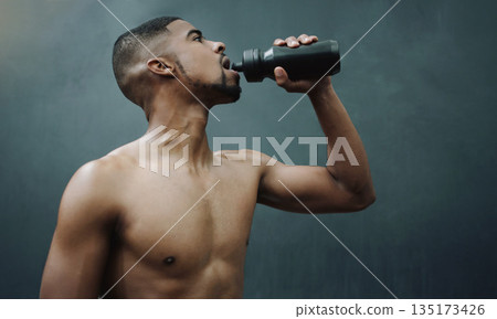 Fitness, man and drinking water on wall background after workout, exercise and training at a gym. Bottle, hydration and male relax after cardio, bodybuilding or challenge at sports center with space 135173426