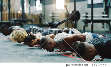 Fitness, sports club and people do push up in gym for training, exercise and workout class. Health, motivation and serious group of men and women body builders for challenge, wellness and strength 135173440