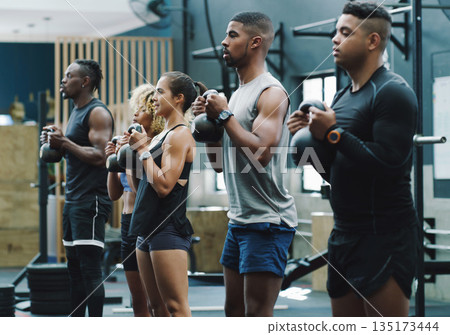 Weightlifting, fitness and people with kettlebell in gym for training, exercise and workout class. Teamwork, body builder and serious men and women lift weights for challenge, wellness and strength 135173444