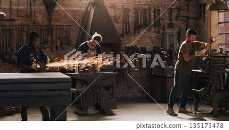Hammer, anvil and sparks with men in a workshop for metal work manufacturing or production. Industry, welding and trade with blacksmith professionals at work in a factory, plant or industrial forge Hammer, anvil and sparks with men in a workshop for metal work manufacturing or production. Industry, welding and trade with blacksmith professionals at work in a factory, plant or industrial forge 135173478
