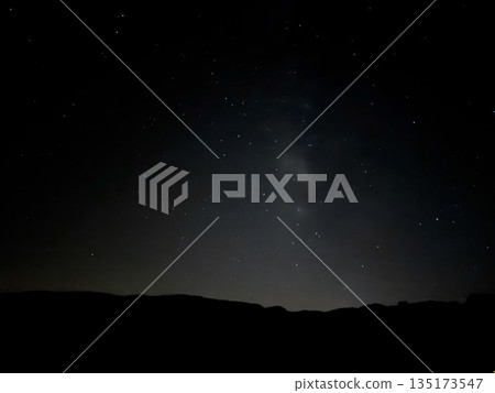 Long exposure photo of the Milky Way arching over dark volcanic mountains at night near Teide Observatory, Tenerife. 135173547
