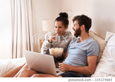 Laptop, watching movie and popcorn with couple in bed for streaming, relax or internet. Subscription, happy and love with man and woman eating at home for social media, funny and free time on weekend Laptop, watching movie and popcorn with couple in bed for streaming, relax or internet. Subscription, happy and love with man and woman eating at home for social media, funny and free time on weekend 135173665