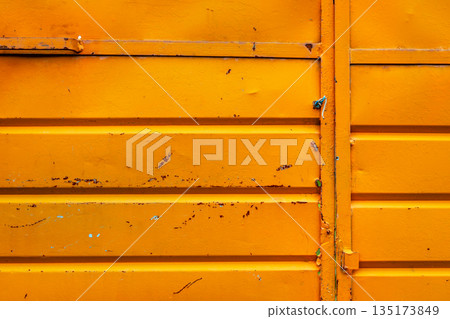 Cracked and rusty orange metal sheet texture close-up 135173849