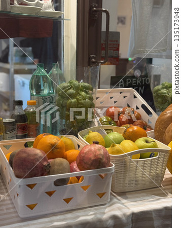 Assorted fresh fruits including persimmons and grapes arranged in crates at a Roman grocery or produce shop. Assorted fresh fruits including persimmons and grapes arranged in crates at a Roman grocery or produce shop. 135173948