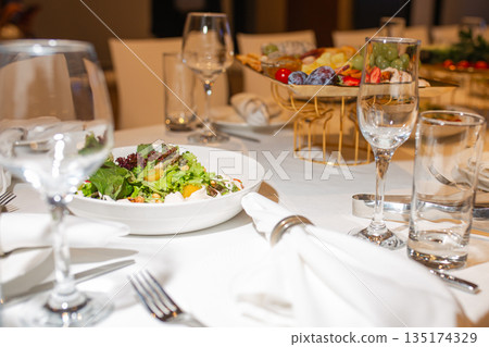 Top view of set table with salad and fruit assortment, elegant table setting for banquet Top view of set table with salad and fruit assortment, elegant table setting for banquet 135174329