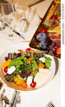 Fresh mixed salad with cheese, vegetables and creamy sauce served in a restaurant setting. 135174347