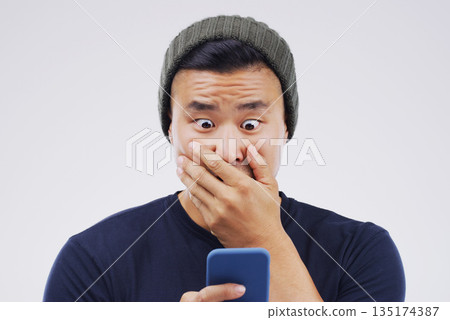 Asian man, surprise and phone in shock for winning, prize or good news against a white studio background. Shocked or surprised male person reading on mobile smartphone in wow for lottery competition Asian man, surprise and phone in shock for winning, prize or good news against a white studio background. Shocked or surprised male person reading on mobile smartphone in wow for lottery competition 135174387
