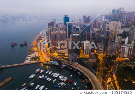 Buildings, ocean and aerial view of the city at night with lights, boats and ships on the sea harbor. Landscape, architecture and drone of an urban town with skyscrapers, yachts and infrastructure. 135174520