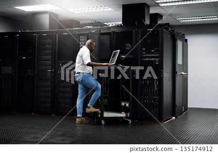 IT support, black man or coding on computer in server room for big data, network glitch or digital website. Code, fixing or technician typing on laptop testing UX, programming or software development IT support, black man or coding on computer in server room for big data, network glitch or digital website. Code, fixing or technician typing on laptop testing UX, programming or software development 135174912