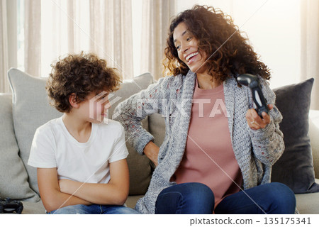 Mother, boy and controller on couch for gaming with loser, competition and contest with laughing in house. Mom, young son and online games on living room couch with upset face for loss in family home Mother, boy and controller on couch for gaming with loser, competition and contest with laughing in house. Mom, young son and online games on living room couch with upset face for loss in family home 135175341