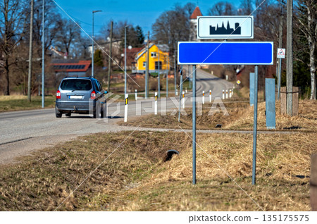 Blank road sign mock-up placed beside a quiet country road on a sunny day 135175575