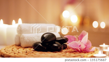 Candles, towels and hot stones at a spa for a massage, healing or luxury treatment therapy. Health, aromatherapy and wellness body care products for a calm, zen or peace atmosphere at a natural salon 135175687
