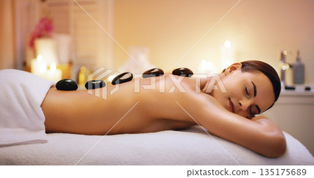 Relax, hot stone and woman getting a massage at a spa for healing, health and wellness. Self care, beauty and female person getting a natural, body care and luxury back therapy or treatment at salon. 135175689