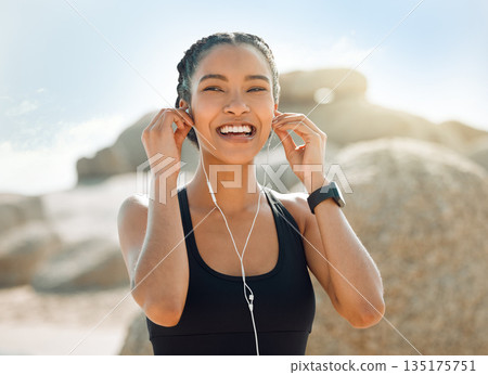 Happy woman with earphones, fitness at the beach and listening to music for motivation and workout outdoor. Exercise, health and smile, female athlete streaming online with radio and audio in nature Happy woman with earphones, fitness at the beach and listening to music for motivation and workout outdoor. Exercise, health and smile, female athlete streaming online with radio and audio in nature 135175751