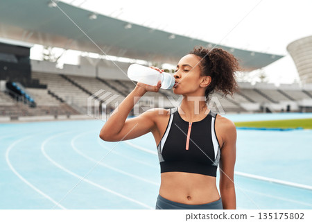 Fitness, running and woman on track drinking from bottle at stadium, relax during marathon training or exercise. Workout time, health and wellness, healthy female sports runner at area with water. 135175802