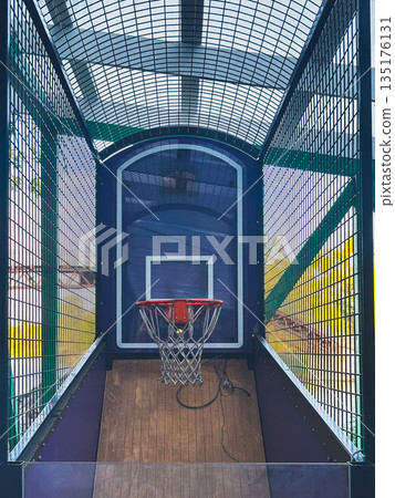 Arcade basketball hoop inside metal cage with wooden floor. 135176131