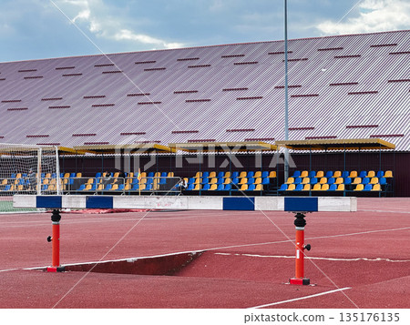 Outdoor stadium with track and empty blue-yellow bleachers. Outdoor stadium with track and empty blue-yellow bleachers. 135176135