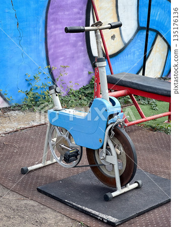 Vintage exercise bike set against colorful graffiti wall 135176136
