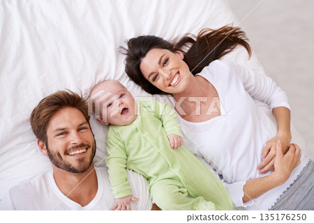 Top view, portrait and happy parents with baby on bed for love, care and quality time together at home. Smile of mother, father and family with cute newborn kid relaxing in bedroom, fun and happiness 135176250